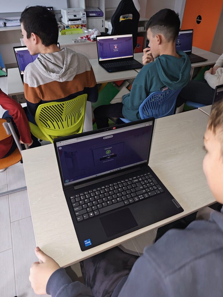 Elevi se uită la laptop-uri
