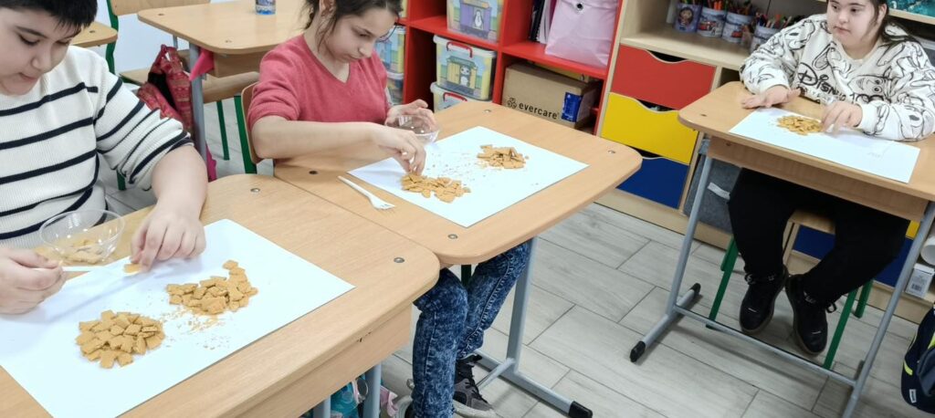 Elevii așează straturile de biscuiți în castron