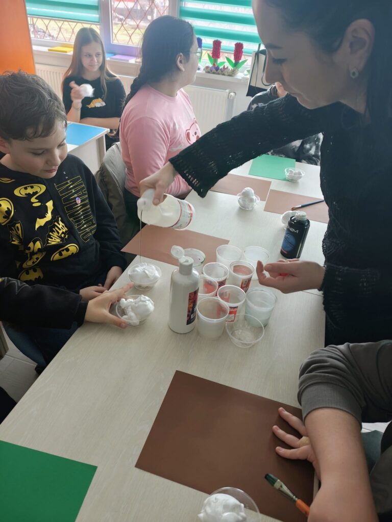 Doamna profesoară îl ajută pe un elev să pregătească spuma