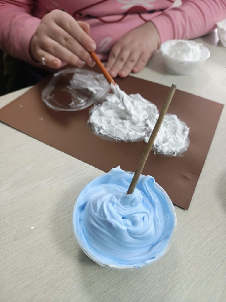 Bol cu spună colorată, elev care amestecă spuma cu lipici