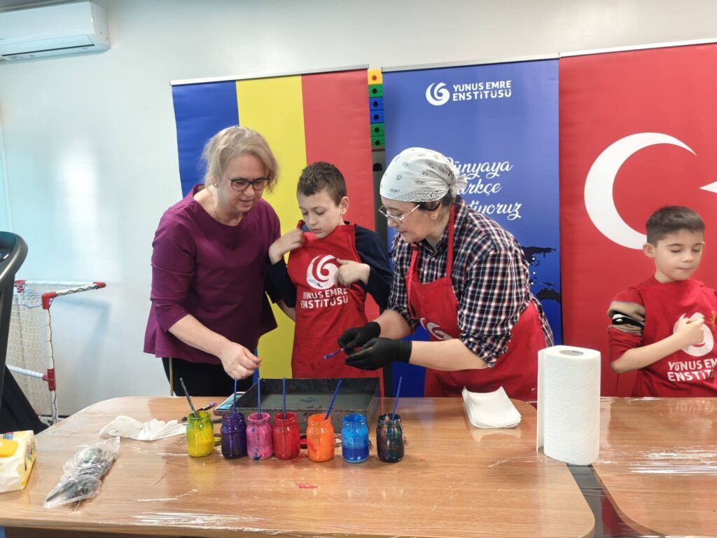 Elev pictează pe apă alături de profesoare în fața steagurilor român și turc