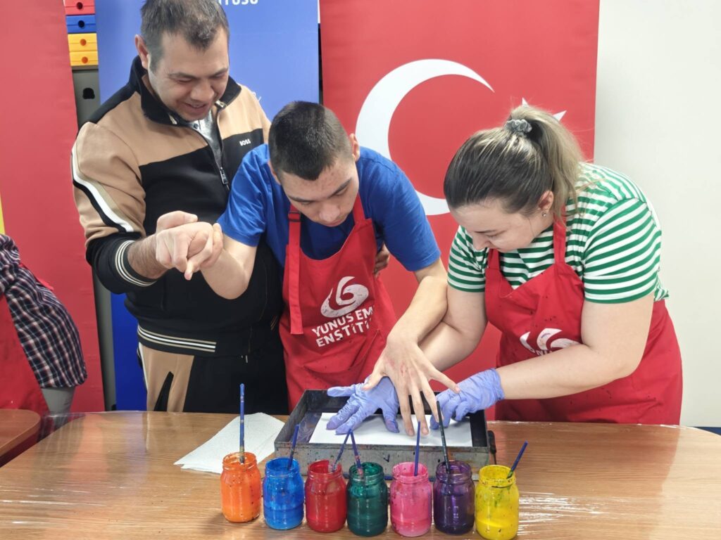 Elevul realizează pictură pe apă sprijinit de tată și doamna profesoară