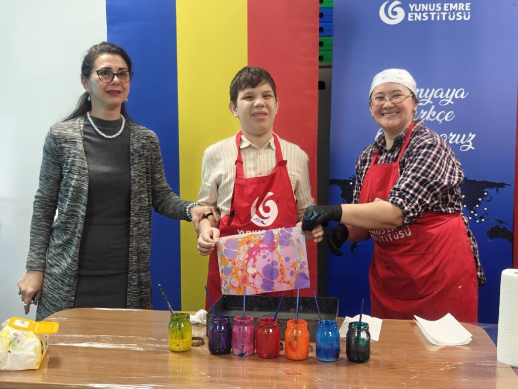 doamna profesoară, doamna de la Yunus Emre și elevul care arată lucrarea realizată