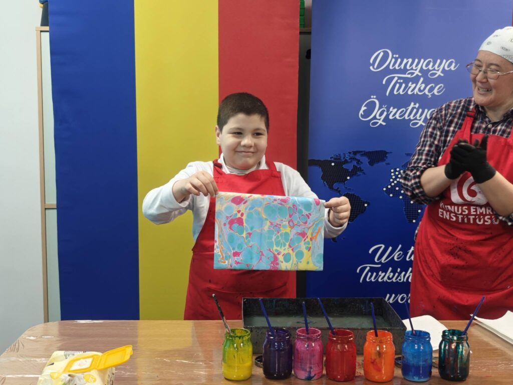 elev arată lucrarea cu picături acvamarin, galben și roz