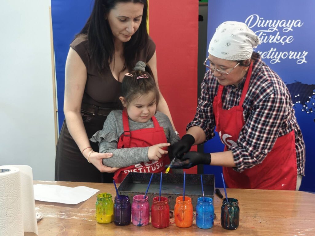 elevă stropește cu galben apa pentru a picta