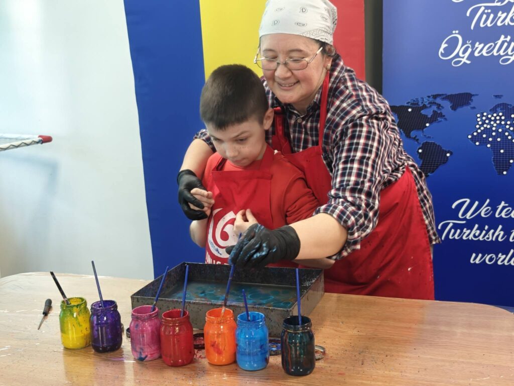 elevul introduce pensula în borcanul roșu