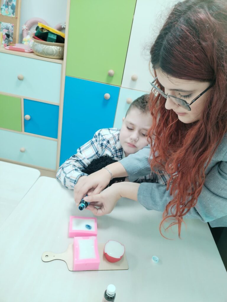 elevul și profesoara toarnă colorant în ceara albă