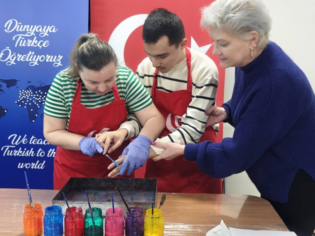 elevul sprijinit de doamna profesoară și doamna de la institut pictează pe apă