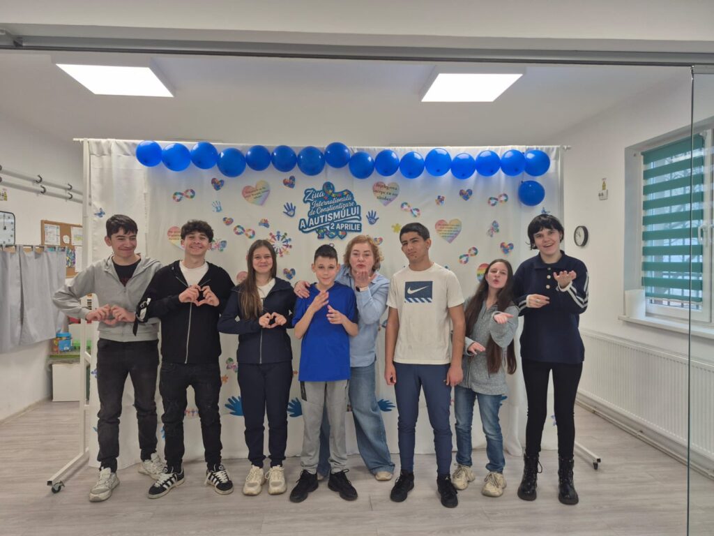 Elevi din clasele mari zâmbesc la poză în fața panoului din sala de kinetoterapie