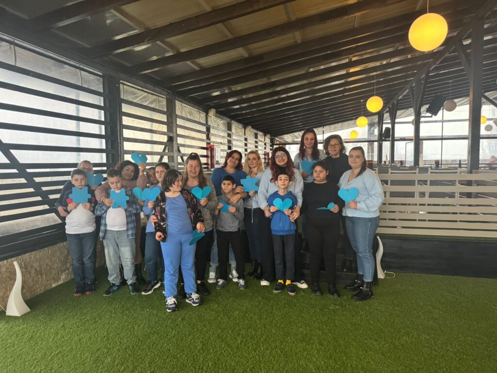 Elevi în vizită la restaurant, zâmbesc și țin inimi de culoare albastră din carton