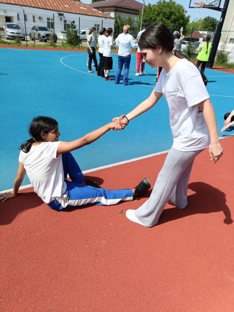 Elevă ajută altă elevă să se ridice de jos
