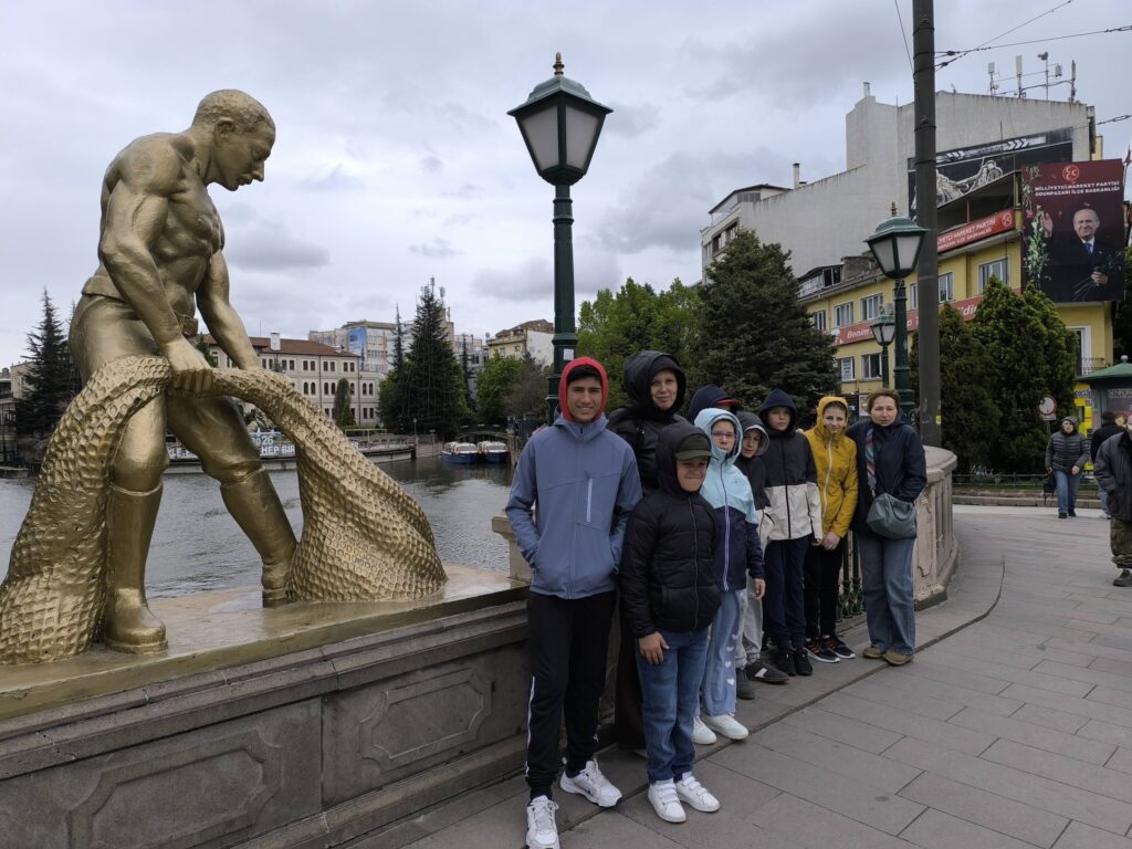 Fotografie de grup în centrul Eskișehir lângă o statuie cu un pescar cu năvod