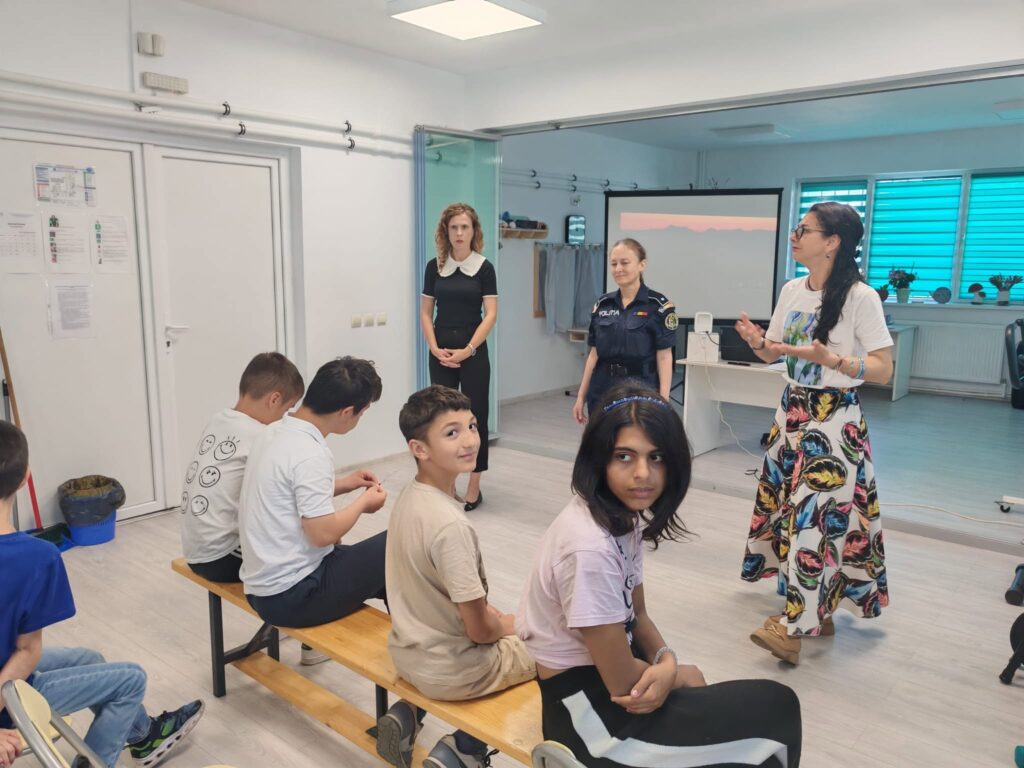 Doamna polițist și doamnele profesoare vorbesc elevilor în fața clasei