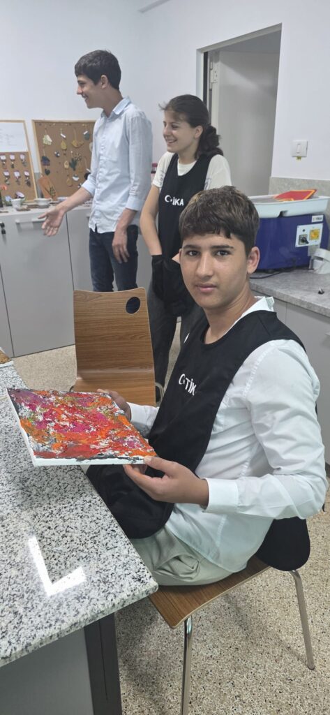 Elev arată planșa realizată din pete aleatorii de culoare roz, oranj.
