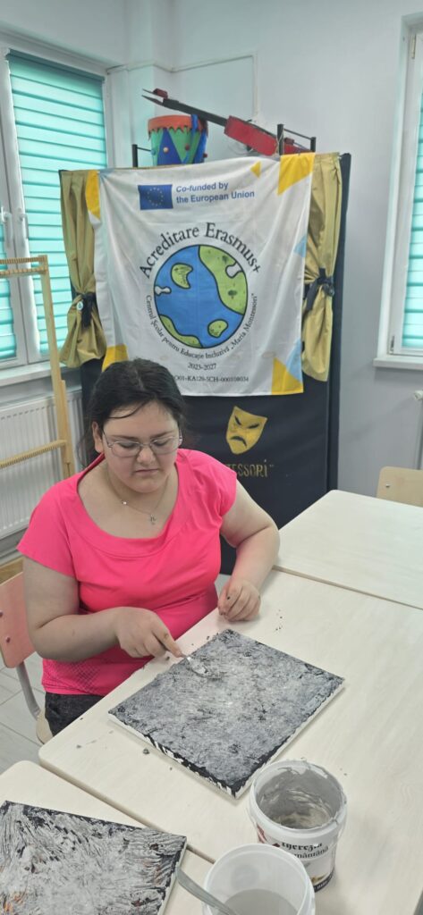 Eleva lângă planșa neagră cu ciment întărit, gata pentru a fi pictată