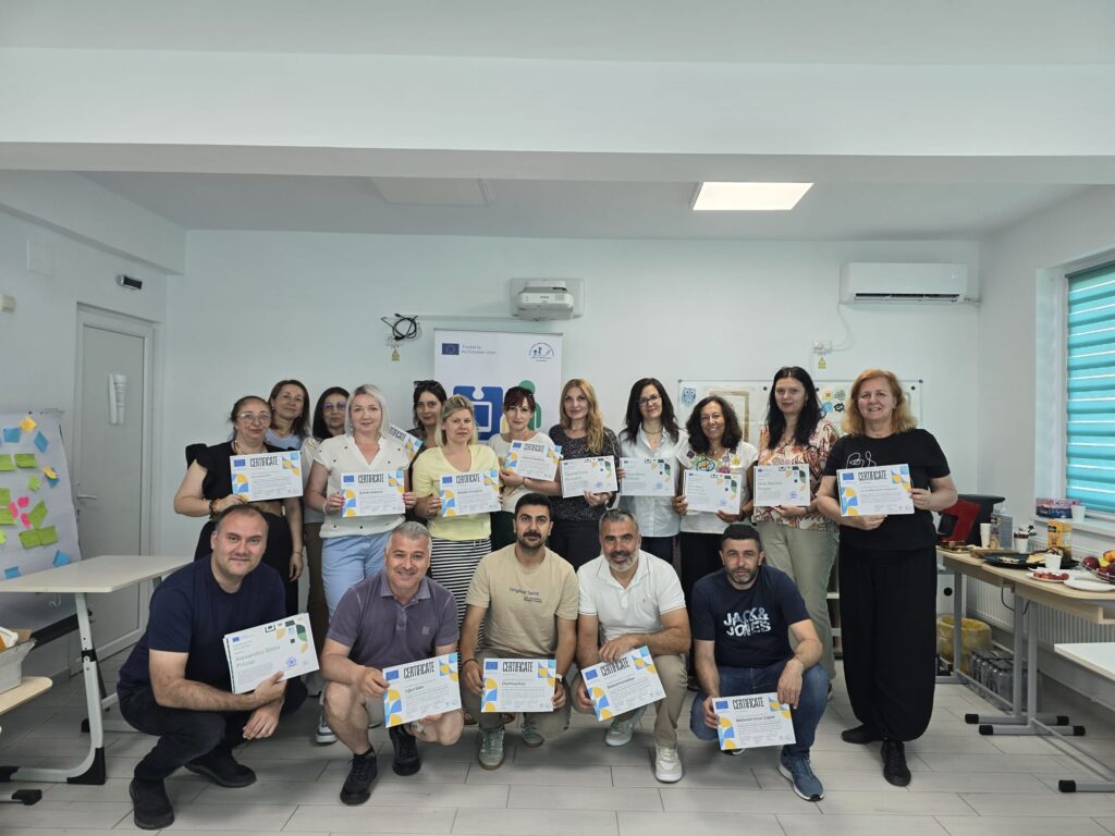 Fotografie de grup cu toți profesorii care au participat la mobilitatea din România, țin diplomele primite.