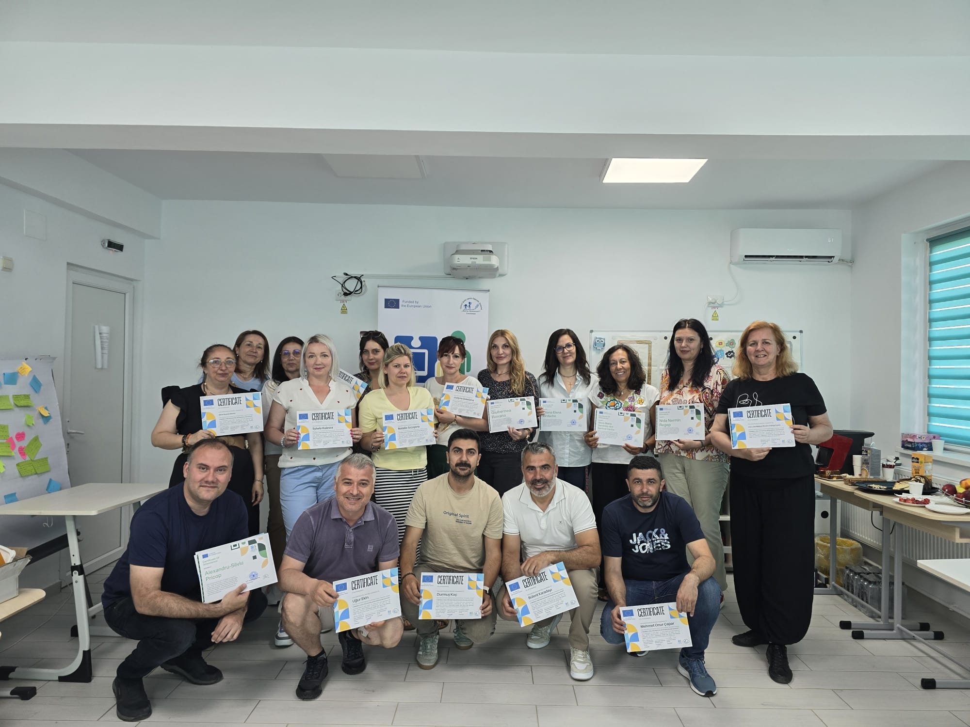 Fotografie de grup cu toți profesorii care au participat la mobilitatea din România, țin diplomele primite.