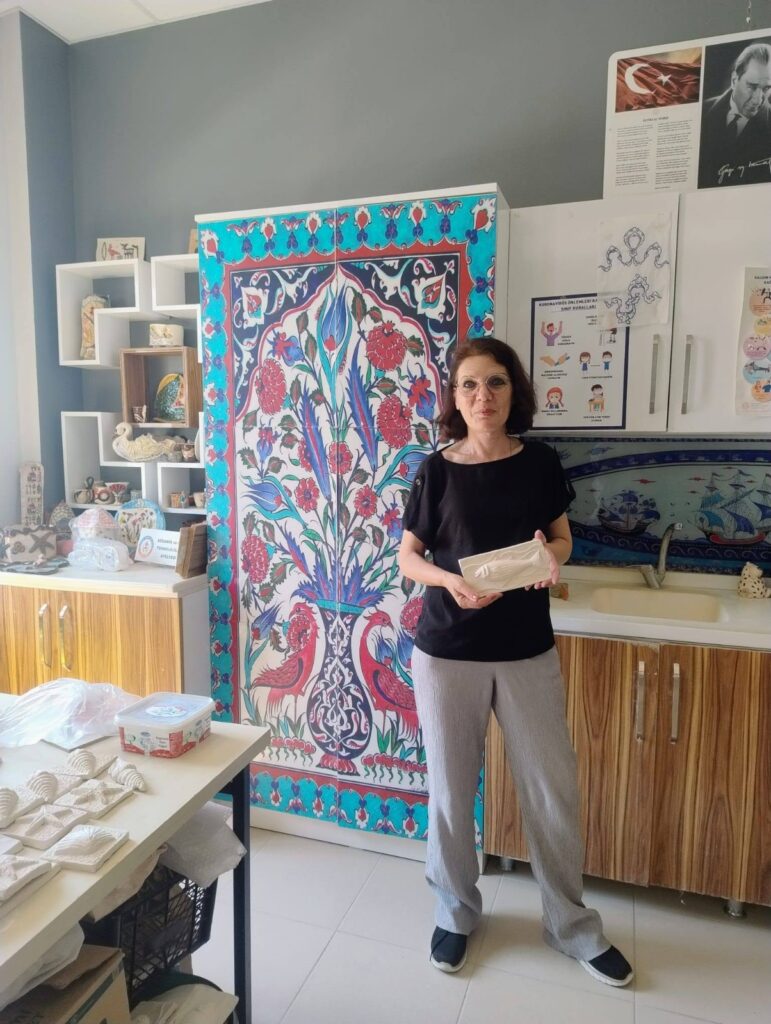 Doamna profesoară lângă un panou decorativ în școala gazdă