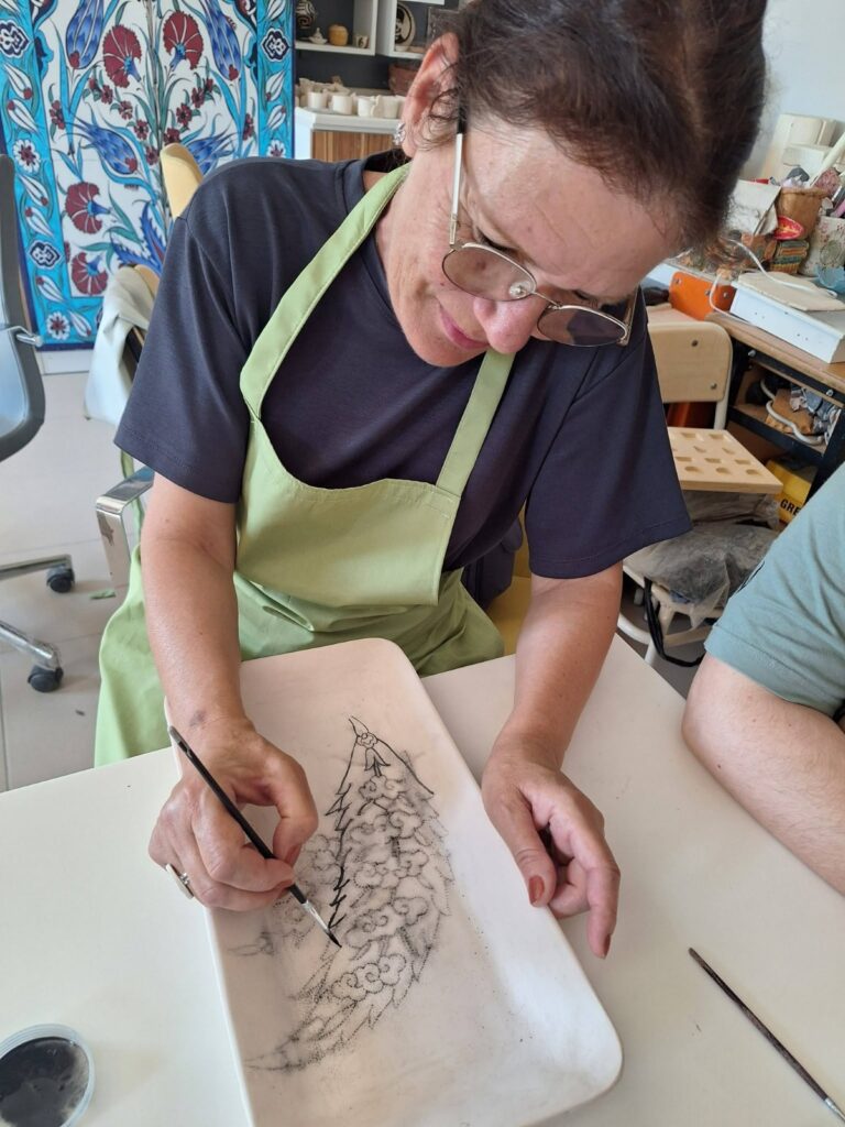 Doamna profesoară pictează o pană pe un vas decorativ