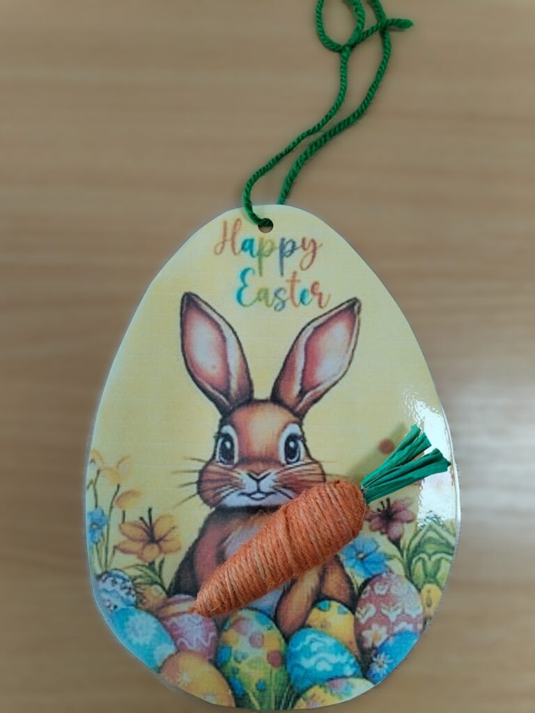 un ou de paște cu un iepure, acesta ține un morcov realizat din hârtie și ață