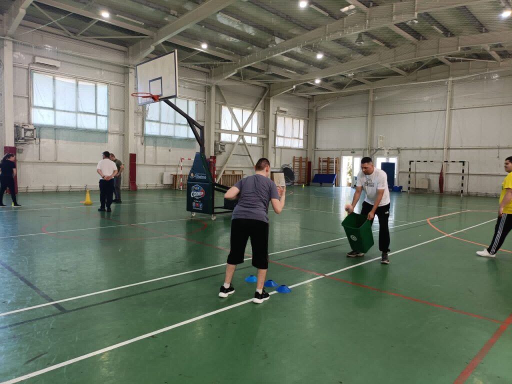 Elevul aruncă mingiuța către coș, ca parte a exercițiilor din traseele aplicative