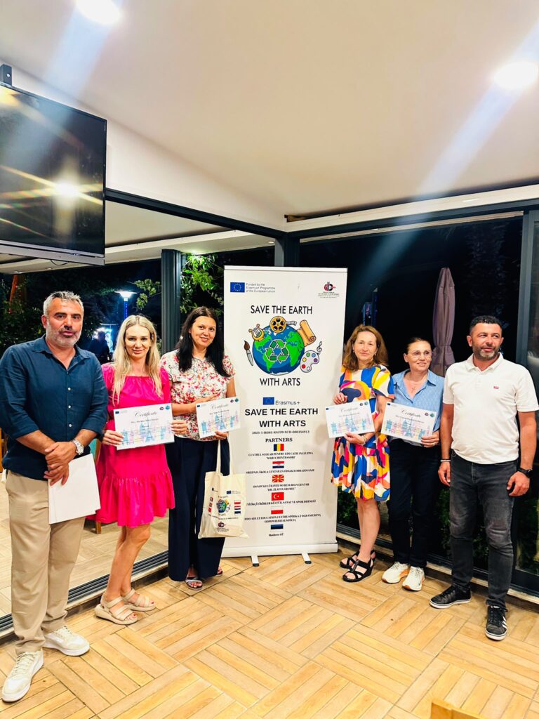 Poză de grup cu profesorii cu diplomele primite lângă bannerul proiectului