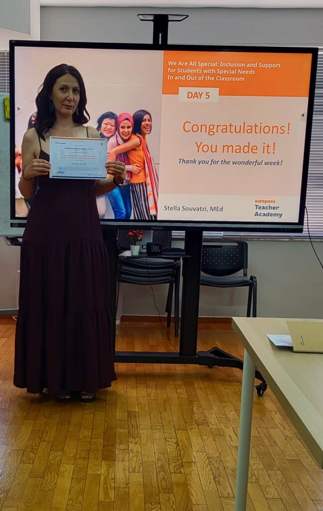 Colega doamnei profesoare cu diploma primită în fața unui panou pe care scrie - Congratulations, You made it!