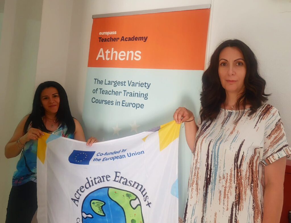 Cadrele didactice lângă posterul firmei formatoare - Europass Teacher Academy țin un banner de prezentare Acreditare Erasmus