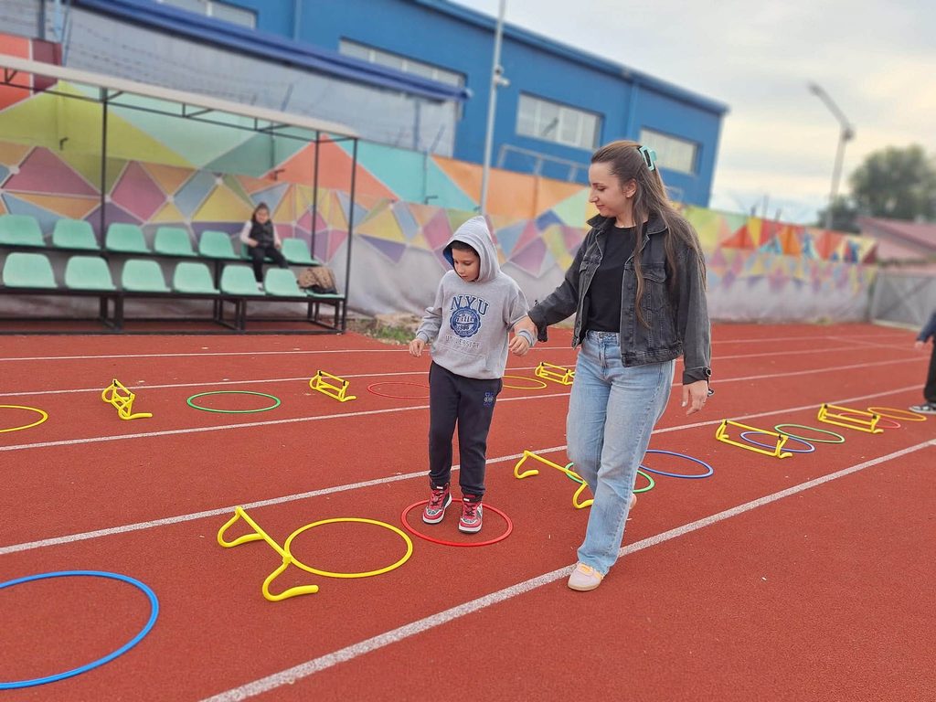 Elevul sprijinit de doamna profesoară parcurge traseul adaptat