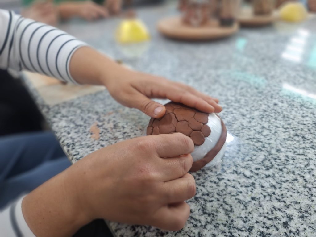 Mână care modelează lutul în formă de sferă