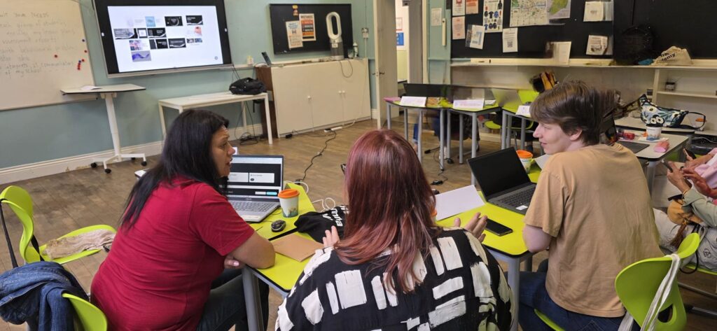 Lucru în echipă: trei cursante discută la laptopuri cum pot crea materiale educaționale cu ajutorul inteligenței artificiale.