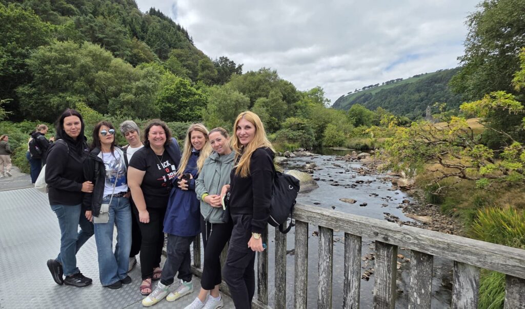 Grupul de profesoare pe un pod de lemn peste un râu de munte, în timpul excursiei la Glendalough.