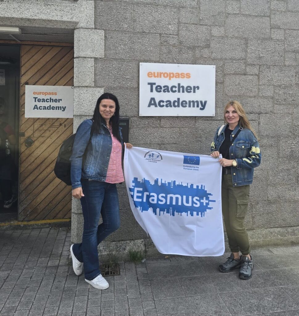 Doamnele profesoare Regep Nida Nermin și Giubermea Roxana țin steagul Erasmus+ al CȘEI „Maria Montessori” Constanța la intrarea în Europass Teacher Academy din Dublin.
