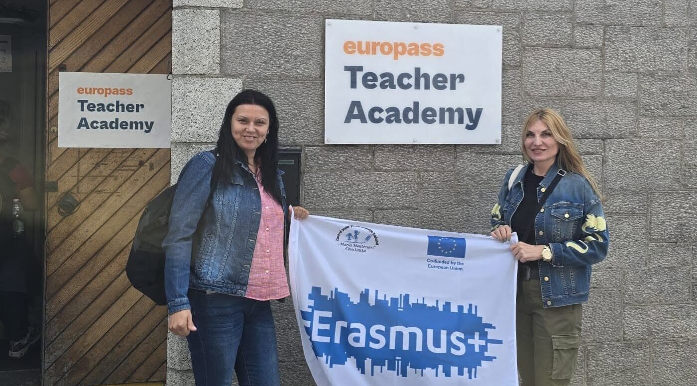 Doamnele profesoare Regep Nida Nermin și Giubermea Roxana țin steagul Erasmus+ al CȘEI „Maria Montessori” Constanța la intrarea în Europass Teacher Academy din Dublin.