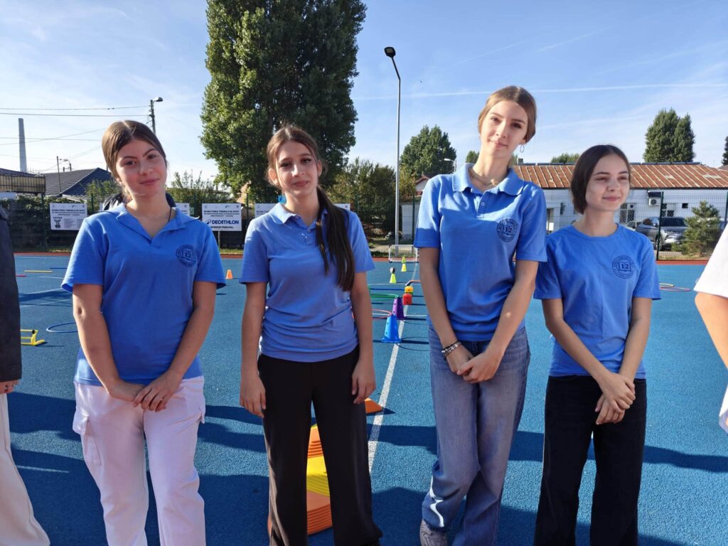 Patru eleve de la Școala Gimnazială Nr. 12 „B.P. Hasdeu”, în tricouri polo albastre, pe terenul de sport.