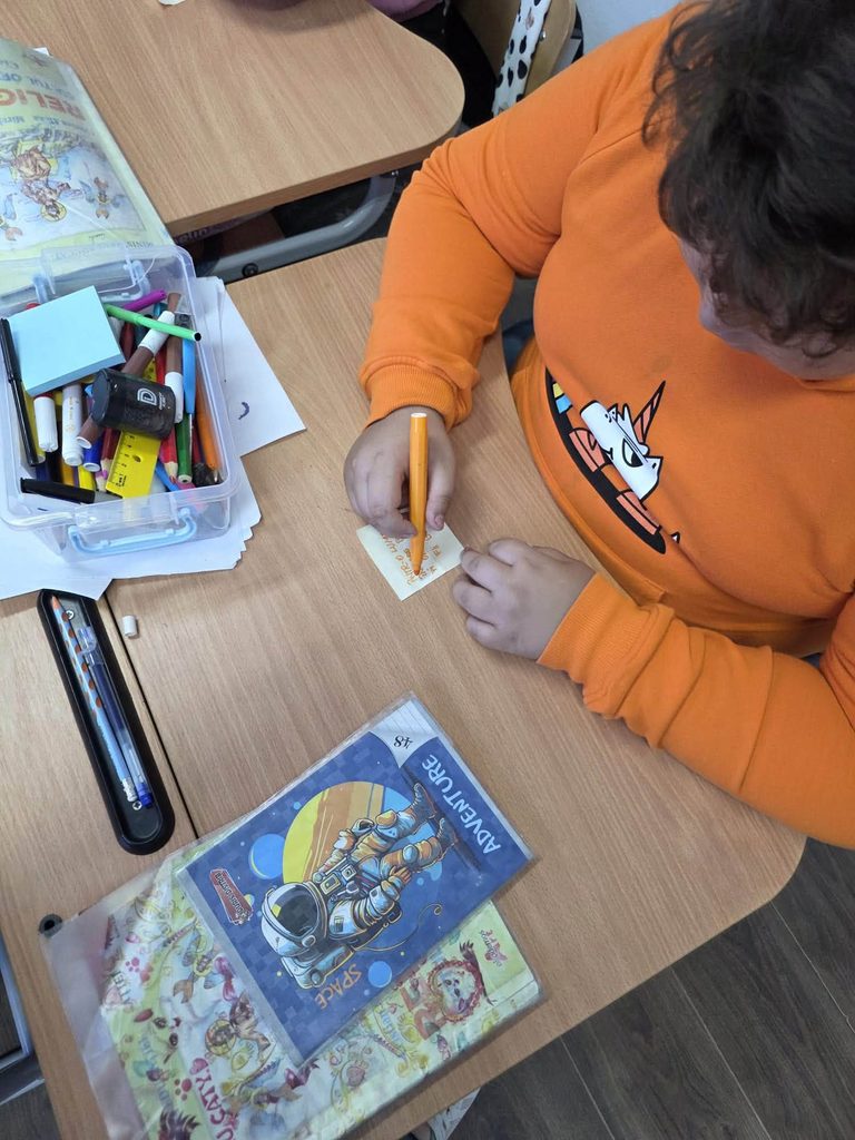 Elev realizează etichete pentru panoul activității